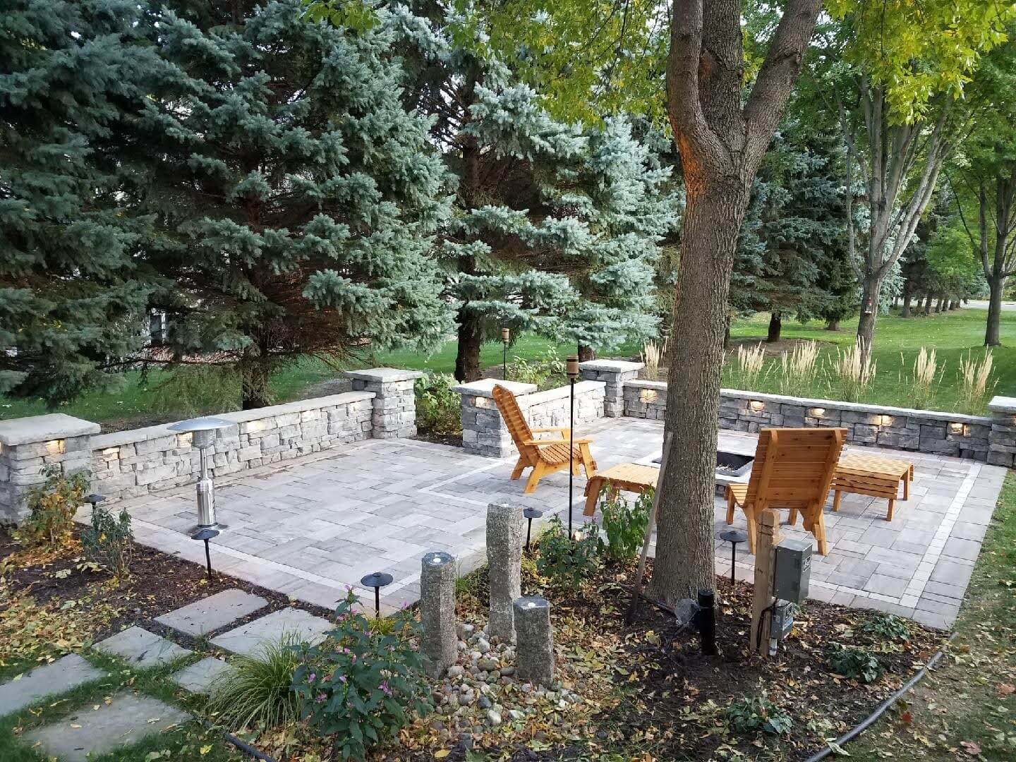 A beautiful seating area on a paver patio nestled in a woodsy location