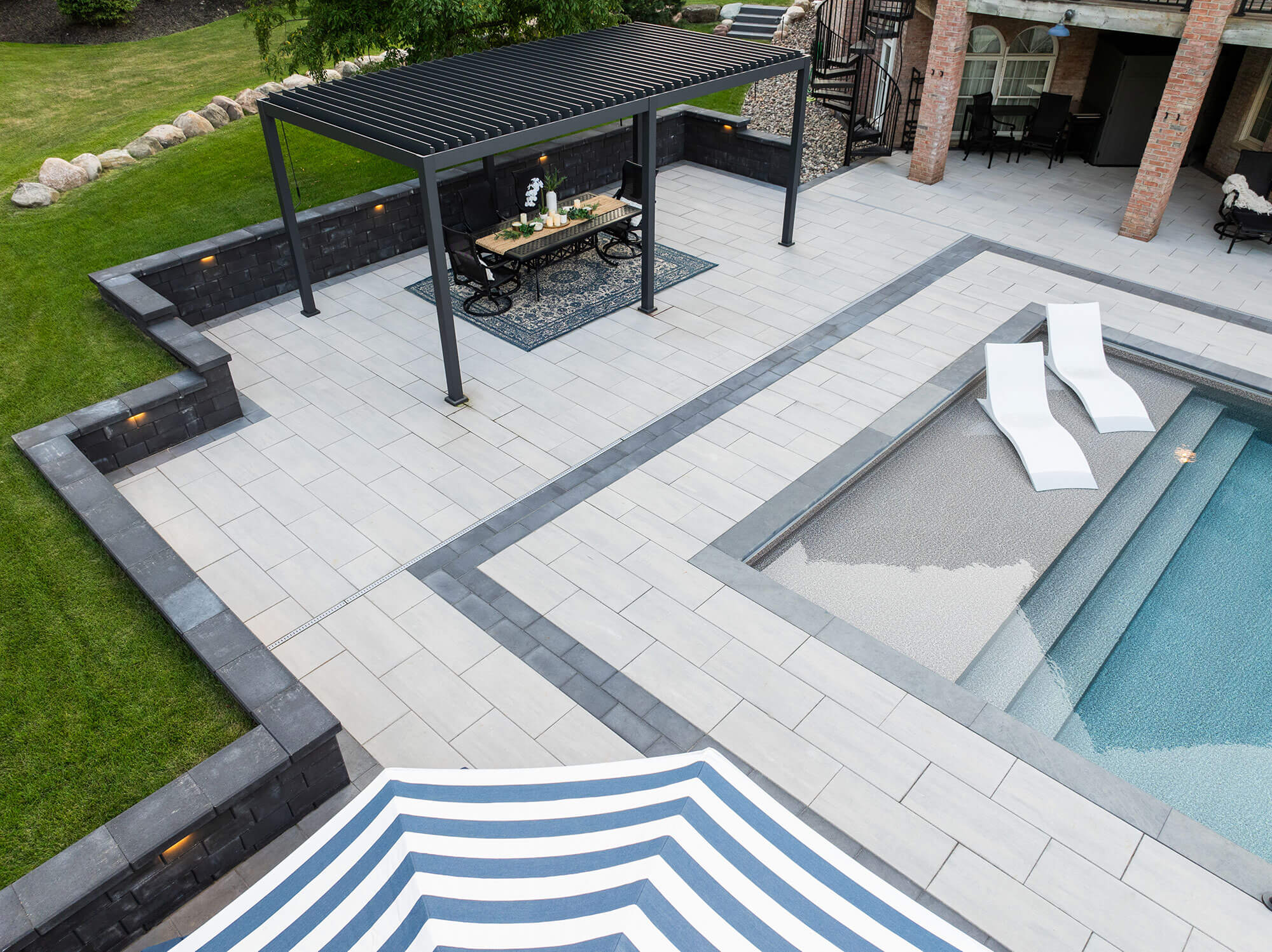 An overhead shot showing a pool, pergola, and retaining wall, all featuring a sleek modern design