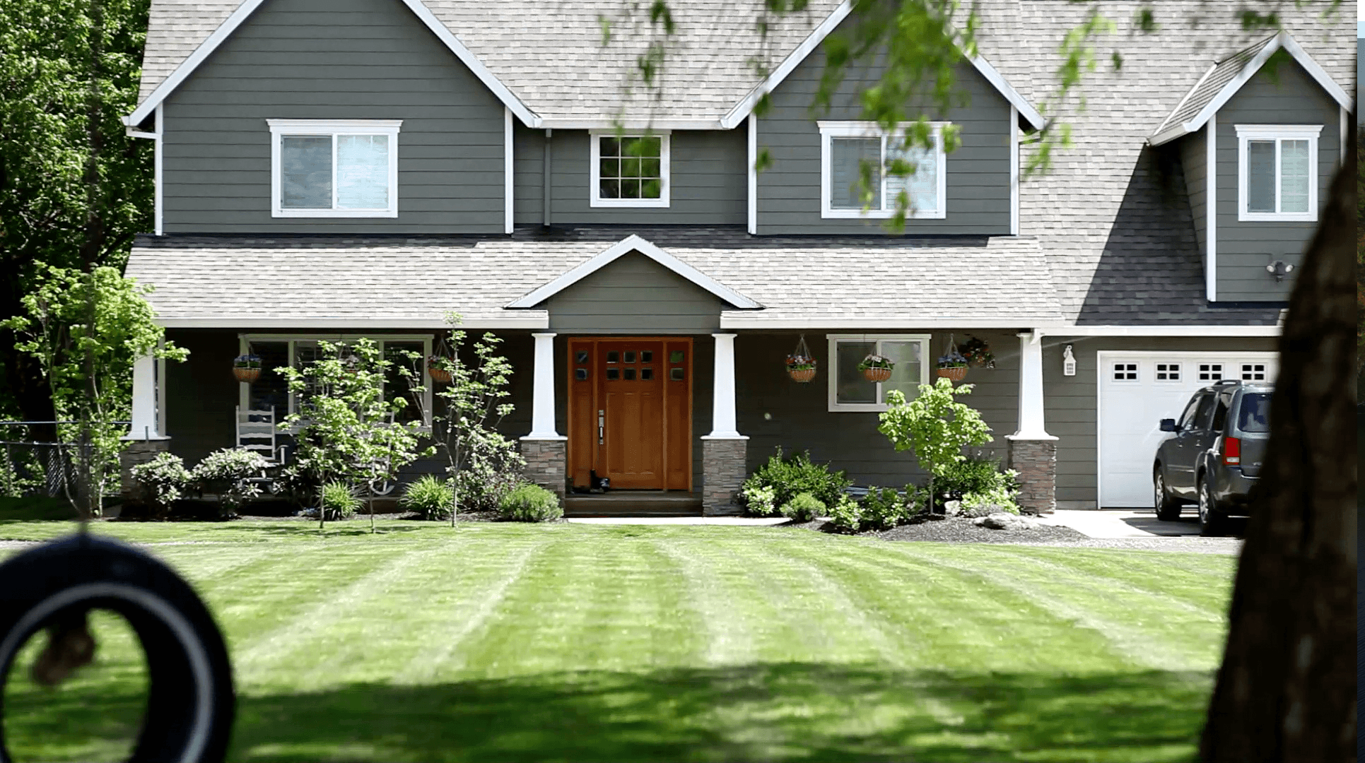 A well-maintained front yard featuring neatly striped lawn grass and some landscaping around the front of the house