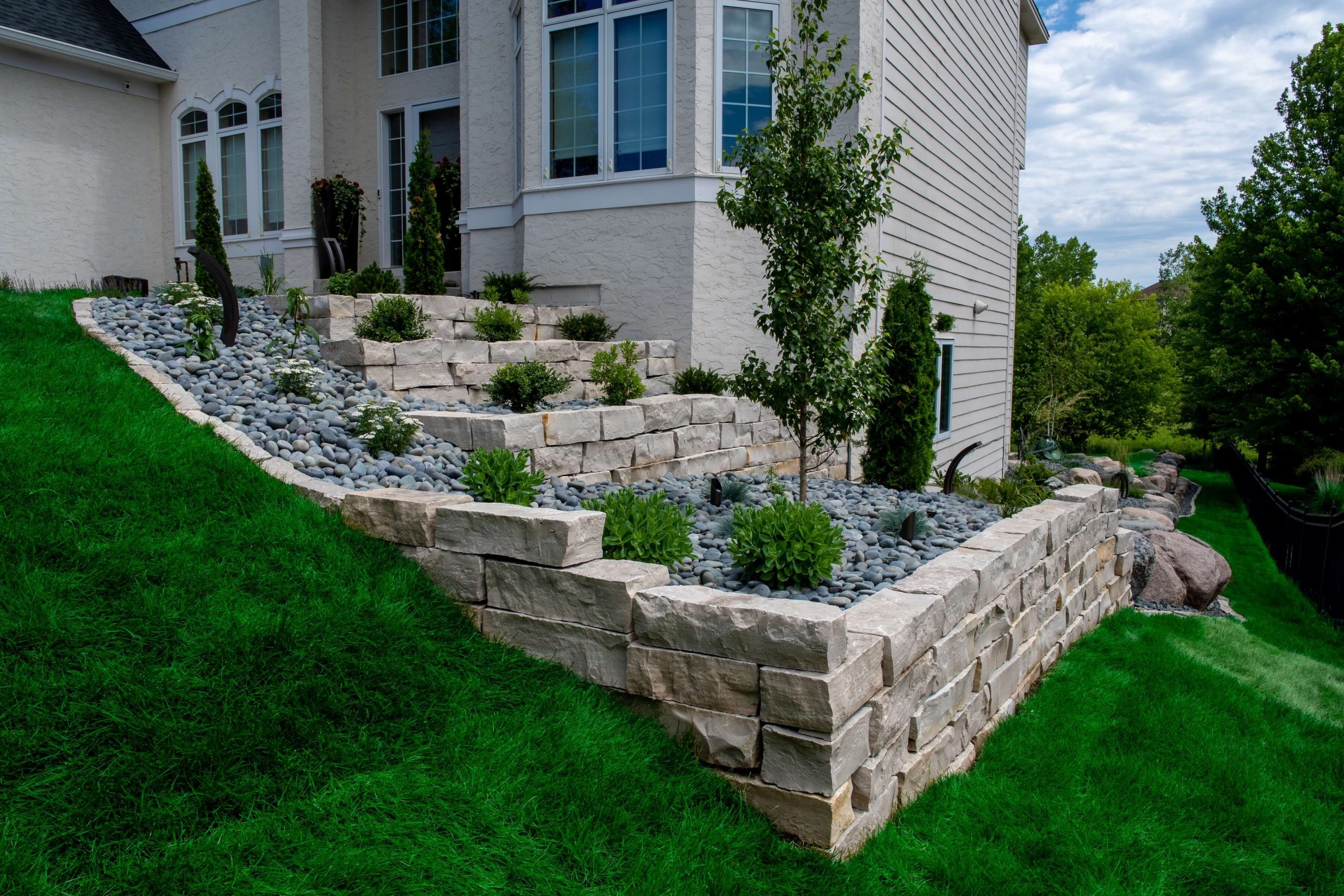 A terraced retaining wall following a steep incline in the yard of a house