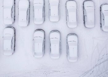 Aerial view of a snowy parking lot with numerous snow-covered cars
